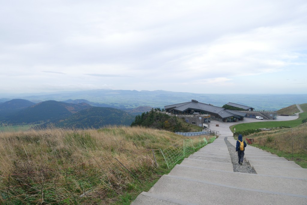 enfin descendant un chemin vers un bâtiment en haut du puy de Dôme
3 volcans en fond