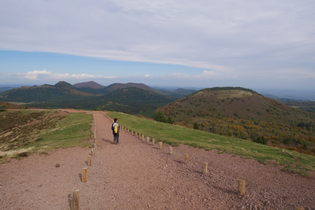enfant sur un chemin en terre
volcan de la chaine des puys en fond