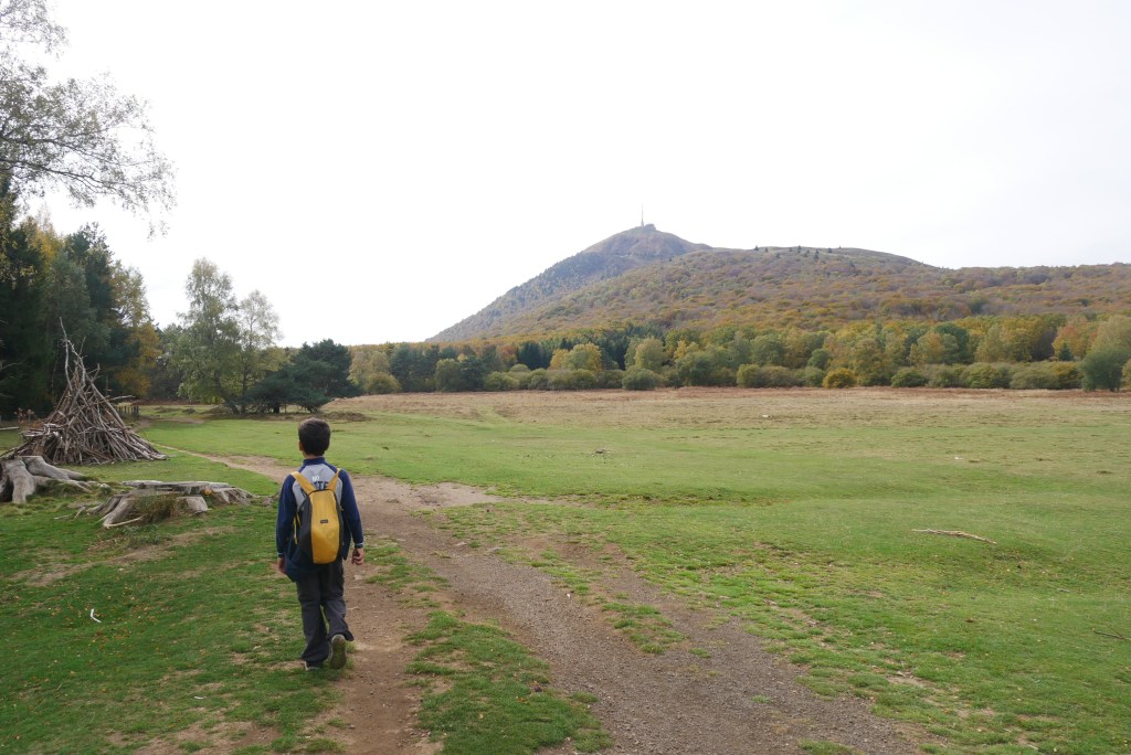 enfin sur un sentier dans une prairie verte
forêt au loin et volcan puy de dôme en fond
