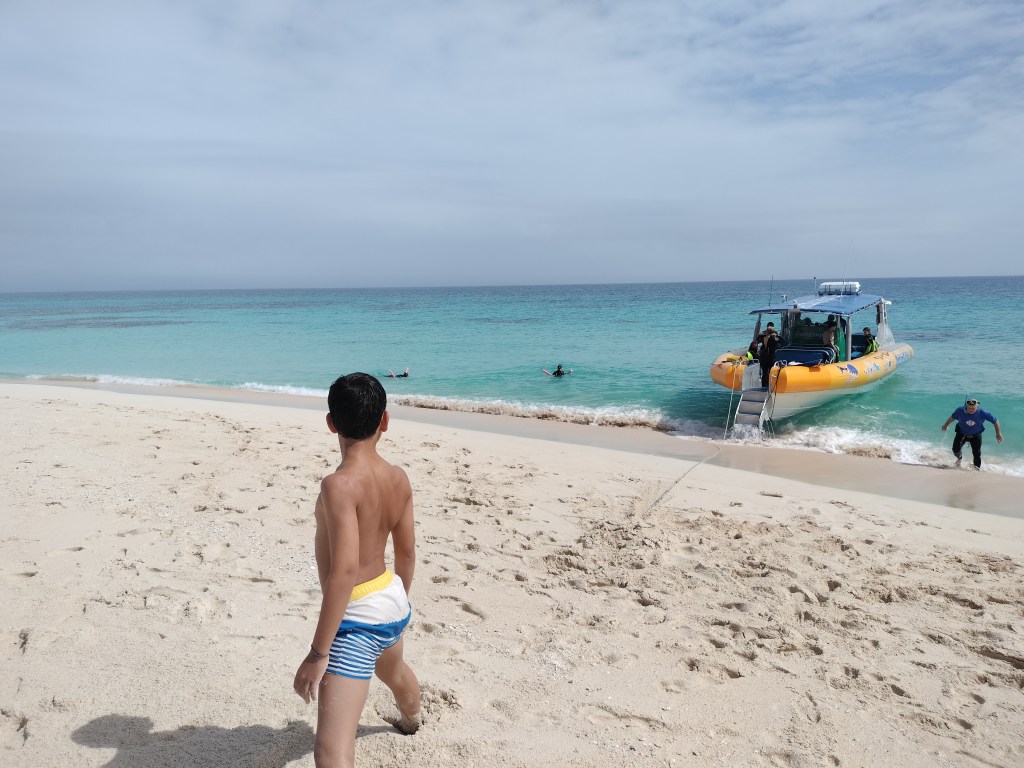 Enfant sur sable blanc, bateau ocean safari cap tribulation