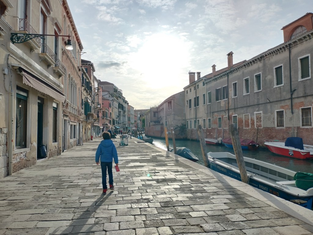 Enfant marchant sur les pavés le long d'un canal à Venise