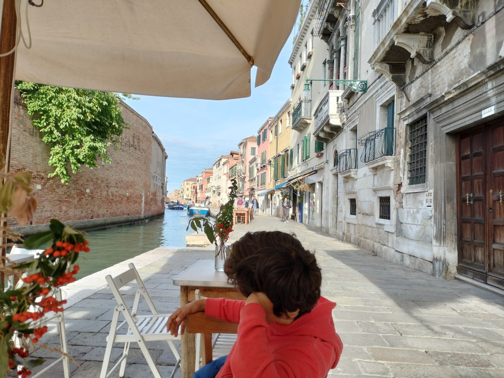 Enfant assis au café Sullaluna au bord du canal à Venise Cannaregio